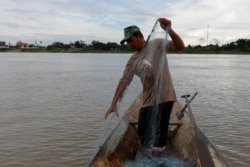 A fisherman pulls a fishing net from his boat in the Mekong River in Nakhon Phanom, Thailand, July 24, 2019.