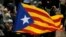 An Independence flag waves during a demonstration outside the regional presidential palace in Sant Jaume Square in Barcelona, Spain, Nov. 2, 2017. Thousands of people rallied in a show of support for ousted Catalan cabinet members and lawmakers appearing in court in Madrid for questioning as part of an investigation into possible rebellion charges for having declared the region’s independence from Spain. 