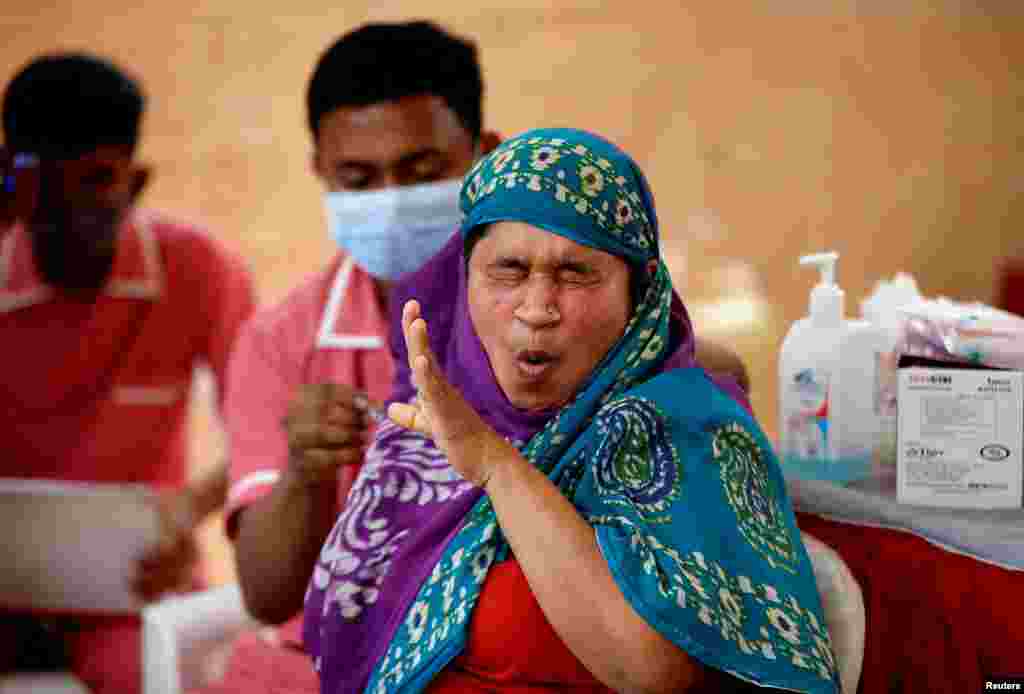 A woman reacts as she receives a dose of the COVISHIELD vaccine at a vaccination center in Ahmedabad, India.
