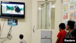 FILE - A detained immigrant child watches a cartoon with other young detained immigrants at a U.S Customs and Border Protection detainee processing facility in Tucson, Ariz., June 28, 2018. 