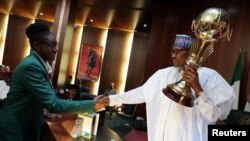 Le président nigérian Muhammadu Buhari lors de la présentation du trophée remporté par l’équipe nationale féminise du basketball du Nigeria à la FIBA, avant son premier conseil des ministres depuis son retour des soins de santé, à Abuja, Nigeria, 30 août 