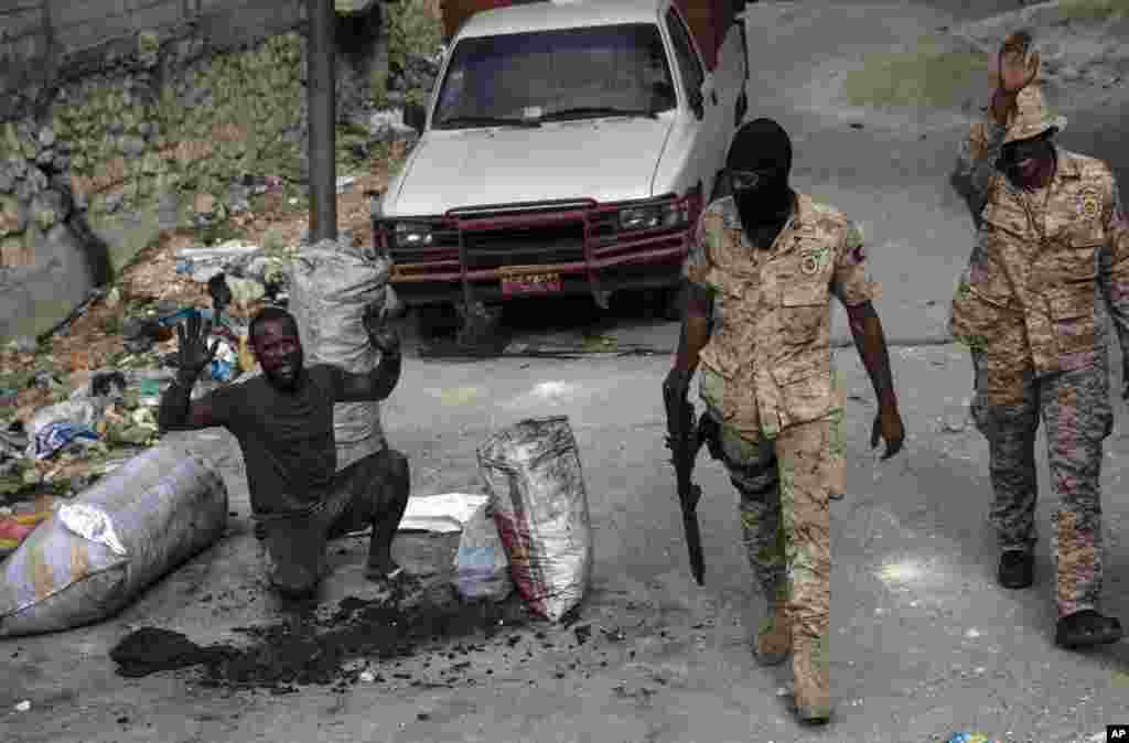 A man raises his arms as police officers patrol the streets in downtown in Port-au-Prince, Haiti, Sept. 22, 2021, where residents set up a barricade in protest after accusing police of killing a man during a raid Tuesday night.