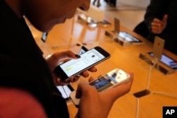 FILE - A customer checks out the new iPhone 6 at an Apple store in Paris, Sept. 19, 2014.