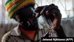 Un toxicomane chauffe un gramme de crystal meth à Glen View township, Harare, le 9 juin 2021.