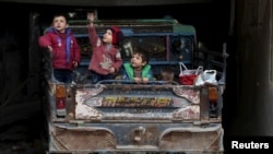 A boy gestures as he sits with others on a pickup truck in the rebel held Douma neighborhood of Damascus, Syria, March 2, 2016.