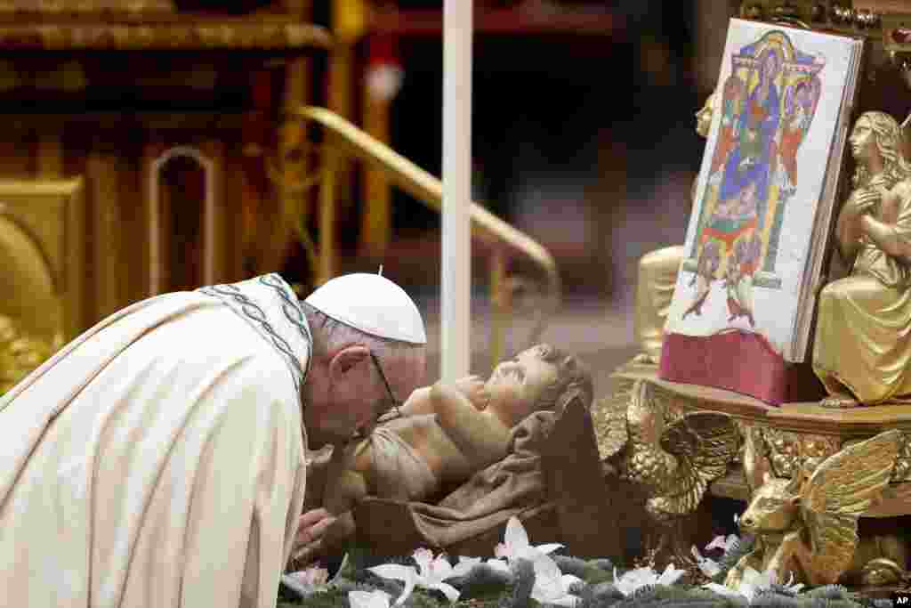 Paus Fransiskus mencium patung Bayi Yesus saat merayakan Misa malam Tahun Baru di Basilika Santo Petrus, Vatikan.