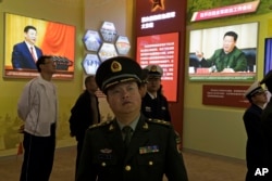 A Chinese military officer walks past photos of Chinese President Xi Jinping at an exhibition highlighting China's achievements under five years of Xi's leadership at the Beijing Exhibition Hall in Beijing, China, Oct. 17, 2017.