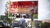 A Uighur ethnic minority man looks at a poster that reads "Don't forget the party's kindness. Don't forget the warmth of the motherland. Don't forget the struggles of each minority group" in the town's market Bazaar in the city of Hotan, China.