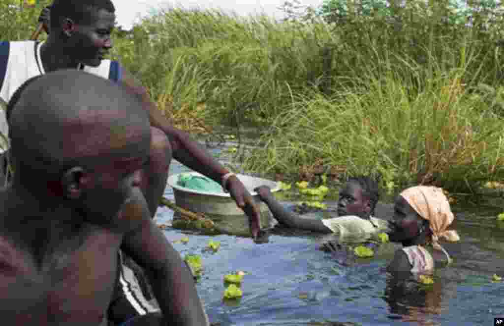 Une femme de l&rsquo;ethnie Nuer retourne à son village après une marche longue d&rsquo;une journée à travers une eau boueuse atteignant la poitrine où elle allait vendre des cas de braise aux déplacés au marché d&rsquo;un camp situé près de la Mission Onusienne au Sud Soudan (UNMISS) au village de Bentiu, au Sud Soudan. 