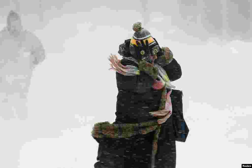 A woman holds onto her hat against the wind during a snow storm in Boston, Massachusetts. Boston, already buried under 60 centimeters of snow from a blizzard last week, was predicted to see a foot of snow after a huge winter storm hit the northeastern United States.