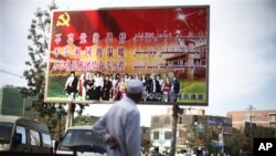 A Uighur ethnic minority man looks at a poster that reads "Don't forget the party's kindness. Don't forget the warmth of the motherland. Don't forget the struggles of each minority group" in the town's market Bazaar in the city of Hotan, China.