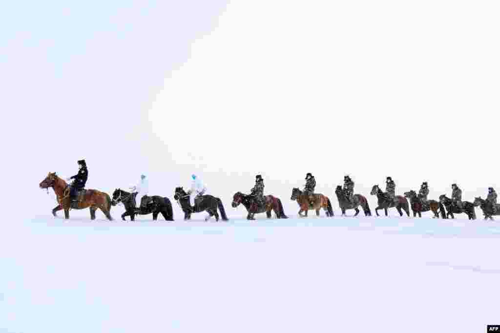 Police officers wearing protective face masks ride horses on their way to visit residents who live in remote areas in Altay, farwest China's Xinjiang region, to promote the awareness of the coronavirus, Feb. 19, 2020.