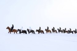 2020年2月19日戴着防护口罩骑马的警察在中国西北新疆偏远地区地区阿尔泰探访居民，宣传应对新冠病毒。