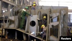 FILE - Workers assemble a part of a ship at a shipbuilding site at the Gdynia shipyard in Poland.