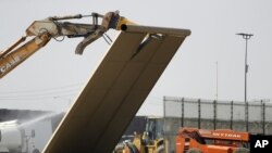 Un prototipo del muro fronterizo cae durante la demolición en la frontera entre Tijuana, México y San Diego, el miércoles 27 de febrero de 2019.