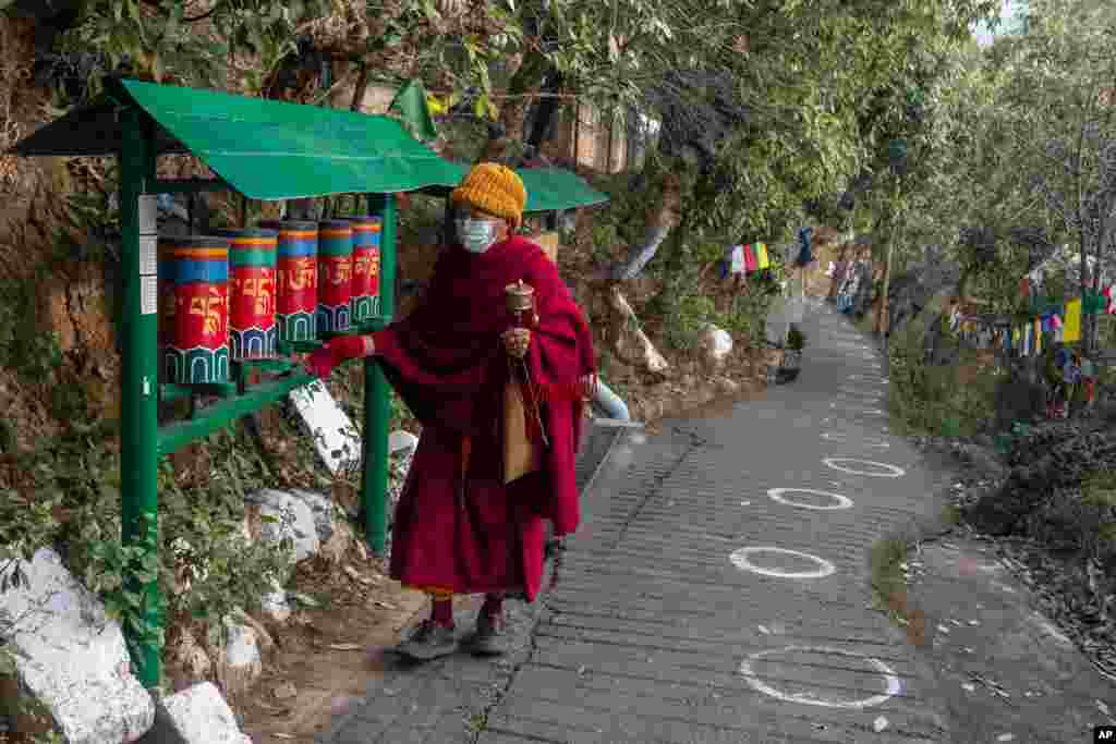An exile Tibetan Buddhist monk rotates prayer wheels next to a path marked with circles for voters to ensure social distancing in Dharmsala, India.