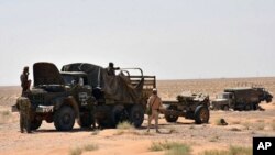 This photo, released Sept. 3, 2017, by the Syrian official news agency SANA, shows Syrian troops and pro-government gunmen standing near military vehicles on the outskirts of the eastern city of Deir el-Zour, Syria.