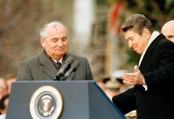 FILE - President Ronald Reagan gestures to Soviet leader Mikhail Gorbachev during arrival ceremonies at the White House, Dec. 8, 1987.