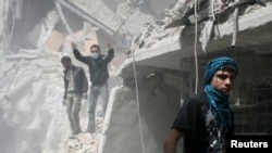 人们在被叙利亚政府军炸毁的瓦砾堆下寻找幸存者