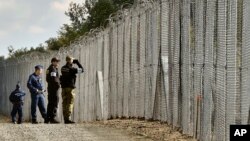 Un policier et un garde-frontière polonais patrouillent avec des policiers hongrois le long de la barrière temporaire à la frontière hongroise-serbe près de Roszke, 180 km au sud-est de Budapest, Hongrie, 13 octobre 2016.