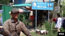 A man driving a motor passing Yim Sokhoeun’s house where a Cambodian People’s Party’s sign bearing the party logo stands in front. “It’s not good unless there is an opposition party,” said Sokhoeun, Jan. 10, 2018. (Sun Narin/VOA Khmer)