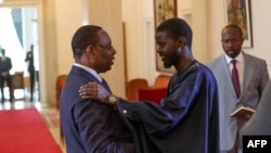 FILE—This picture taken by the Senegalese Presidency on March 28, 2024 shows outgoing Senegalese President Macky Sall (L) greeting Senegal's president-elect Bassirou Diomaye Faye (R) at the Presidential palace in Dakar.