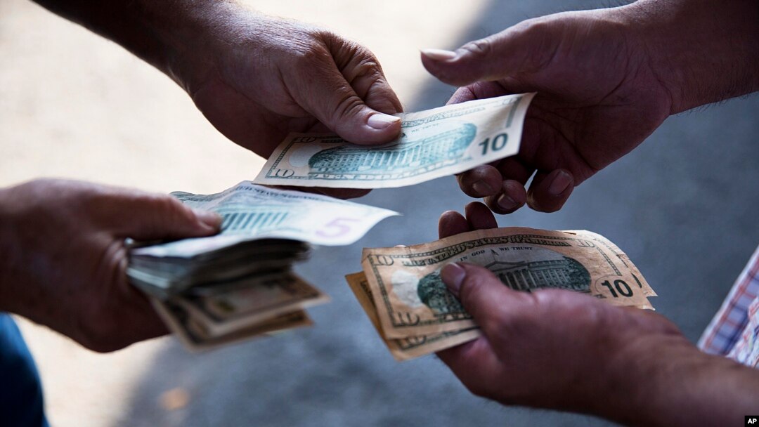 In this June 6, 2015 photo, a customer at left pays for produce with cash to a worker at a stand at the Atlanta Farmers Market. 