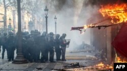 Las fuerzas de la policía antidisturbios se ubican junto al restaurante "Le Fouquet's" que se quema durante los enfrentamientos con las fuerzas de la policía antidisturbios en los Campos Elíseos en París el 16 de marzo de 2019.