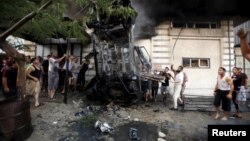 Palestinians inspect a car after it was blown up in Gaza City July 19, 2015. 