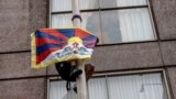 A demonstrator holding a Free Tibet flag climbs a flagpole outside the hotel where China's President Xi Jinping will meet with U.S. business leaders, on the sidelines of the APEC summit, in San Francisco