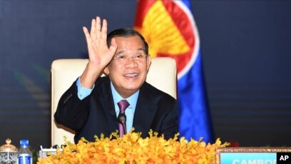 រូបឯកសារ៖ លោក​នាយករដ្ឋមន្ត្រី​ ហ៊ុន សែន លើក​ដៃឡើង ខណៈ​ដែល​លោក​ចូលរួម​កិច្ចប្រជុំ​ពិសេស​អាស៊ាន​-ចិន តាម​អនឡាញ​ពី​ខុទ្ទកាល័យ​នាយករដ្ឋមន្ត្រី នៅ​ភ្នំពេញ ថ្ងៃទី២២ ខែវិច្ឆិកា ឆ្នាំ២០២១។ (An Khoun SamAun/National Television of Cambodia via AP, File)