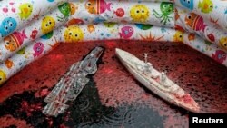 Models of warships are seen in a pool with the blood of animals as members of the Democratic Alliance party take part in a performance in front of the French embassy, Kyiv May 15, 2014.