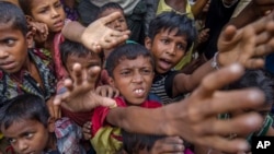 Rohingya Muslim children, who crossed over from Myanmar into Bangladesh, stretch out their arms out to collect chocolates and milk distributed by Bangladeshi men at Taiy Khali refugee camp, Bangladesh, Sept. 21, 2017. 