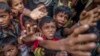 Rohingya Muslim children, who crossed over from Myanmar into Bangladesh, stretch out their arms out to collect chocolates and milk distributed by Bangladeshi men at Taiy Khali refugee camp, Bangladesh, Sept. 21, 2017. 