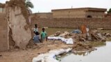 Children sit at the side of a flooded road in the town of Salmaniya, about 25 miles (35 km) southwest of the capital, Khartoum, Sudan, Sept. 17, 2020. 