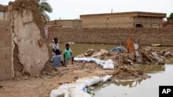 Children sit at the side of a flooded road in the town of Salmaniya, about 25 miles (35 km) southwest of the capital, Khartoum, Sudan, Sept. 17, 2020. 