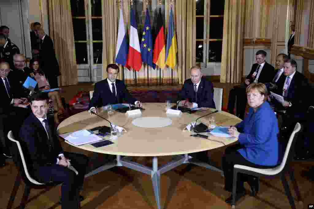 French President Emmanuel Macron, center left, Russian President Vladimir Putin, center right, German Chancellor Angela Merkel and Ukrainian President Volodymyr Zelenskiy, left, attend a working session at the Elysee Palace in Paris, t o find a way to end the five years of fighting in eastern Ukraine.