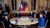 French President Emmanuel Macron, center left, Russian President Vladimir Putin, center right, German Chancellor Angela Merkel and Ukrainian President Volodymyr Zelenskiy, left, attend a working session at the Elysee Palace in Paris, t o find a way to end the five years of fighting in eastern Ukraine.