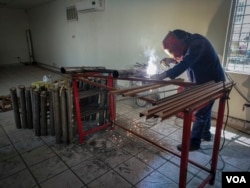 A welder is seen assembling beds at Alfa y Omega migrant shelter in Mexicali, Mexico, in preparation for the Central American caravan's arrival. (R. Taylor/VOA)