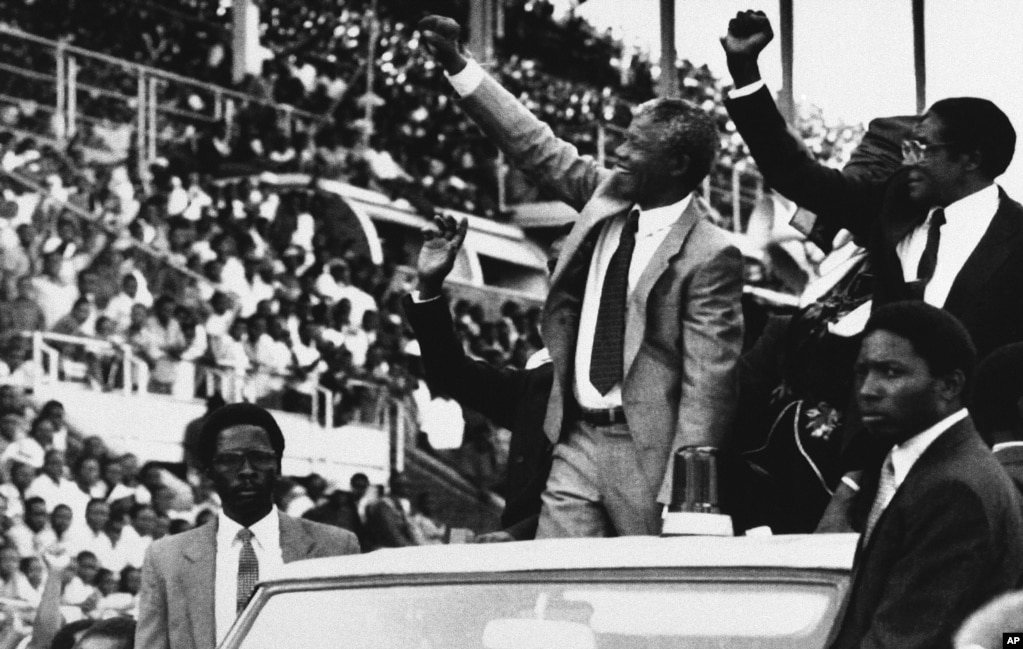 Deputy President of the African National Congress Nelson Mandela, center, and Zimbabwe President Robert Mugabe, far right, greet the crowds at the start of the new Zimbabwe public holiday, Mandela Day, March 5, 1990, Harare, Zimbabwe. (AP Photo)