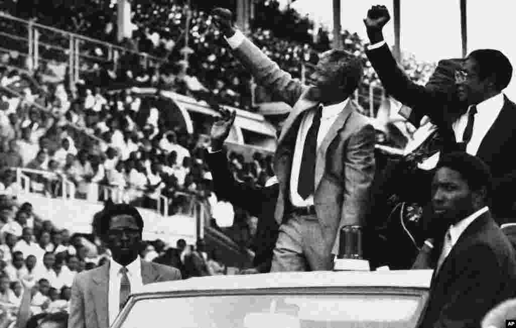 Le vice-président de l&#39;ANC Nelson Mandela, au centre, et le président du Zimbabwe, Robert Mugabe, à droite, saluent la foule au Zimbabwe, pour Mandela Day, le 5 mars 1990, à Harare, Zimbabwe.