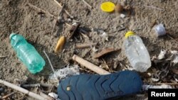 FILE - Plastic bottles and a flip-flop lie on the sand at Maccarese beach in Rome, Italy, Nov. 21, 2018. 