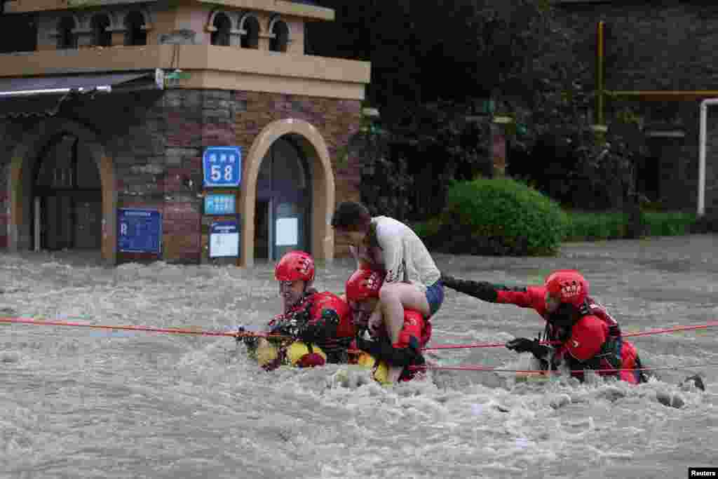 在中国四川省成都市暴雨过后，消防队员在一条被水淹没的街道上救出一名被困女子。