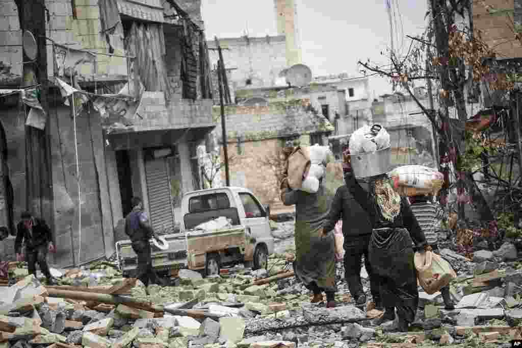 Syrian residents carry their belongings after their homes were damaged due to fighting between Free Syrian Army fighters and government forces in Aleppo, Syria, December 11, 2012.