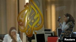 FILE - The Al Jazeera logo is seen through a window at the offices of the Arabic news channel in Ramallah, West Bank.