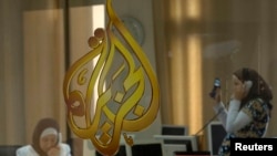 FILE - The Al Jazeera logo is seen through a window at the offices of the Arabic news channel in Ramallah, West Bank, July 15, 2009. 