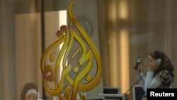 FILE - The Al-Jazeera logo is seen through a window at the offices of the Arabic news channel in Ramallah, West Bank, July 15, 2009.