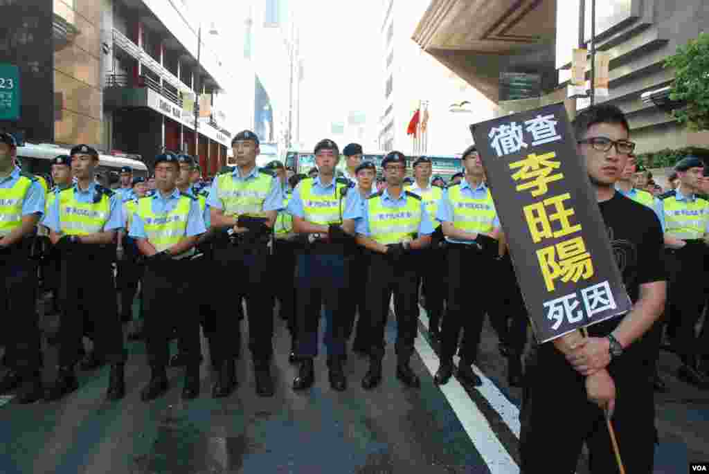 示威者手持标语站在大队警员前示威
