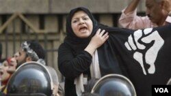 Una manifestante en El Cairo reclama el fin de la violencia policial, frente a un cordón de agentes de seguridad.