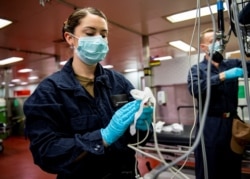 FILE - Hospitalman Katelynn Kavanagh, from Temecula, California, sanitizes medical equipment aboard the Military Sealift Command hospital ship USNS Mercy off the coast of southern California, March 24, 2020. .